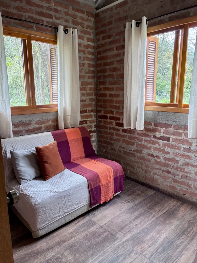 Sala com sofá-cama e manta colorida, vista de outro ângulo